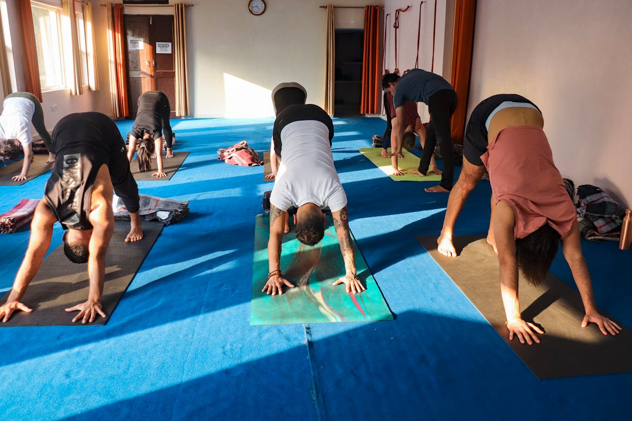 A group of adults practicing yoga in a sunlit studio in Rishikesh, India.
